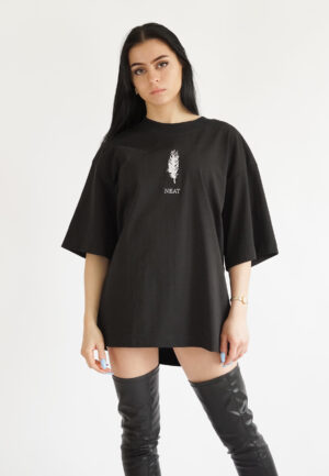 model wearing a black oversized t-shirt with a white feather embroidery and the brand name Neat