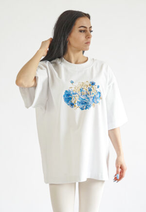 White oversized t-shirt featuring a central blue and gold floral print with Neat logo.