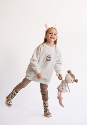 A young girl wearing the cream "Little Hedgehog" sweatshirt, designed for a perfect matching outfit with the women's version by Neat Atelier.