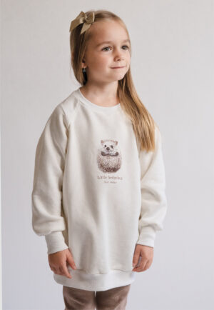 A young girl wearing the cream "Little Hedgehog" sweatshirt, designed for a perfect matching outfit with the women's version by Neat Atelier.